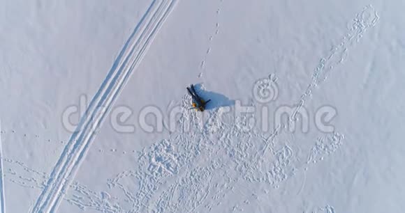 女人躺在雪地里的油管上摄像机慢慢升起空中镜头高视角视频的预览图