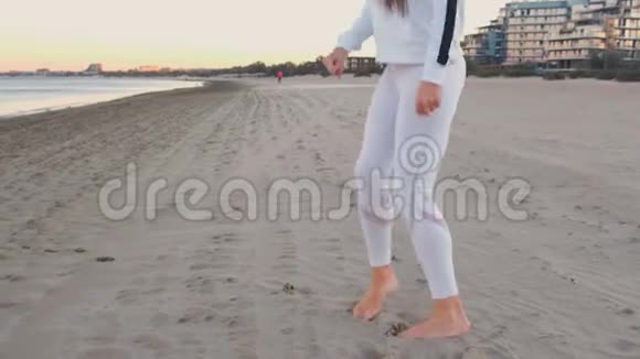 秋日日出时年轻女子正在海边的沙滩上慢跑后景腿部特写视频的预览图