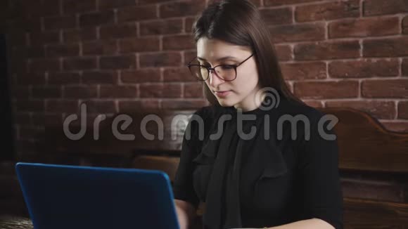 一个年轻女孩在笔记本后面工作的肖像漂亮的女人在笔记本电脑键盘上打字视频的预览图
