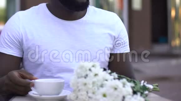 悲伤英俊的非裔美国男人在咖啡馆等女人约会迟到视频的预览图