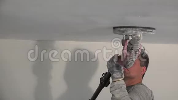 肮脏的泥塑工用砂光机打磨天花板视频的预览图