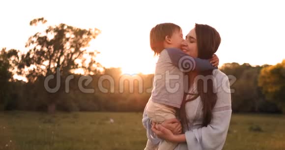 夏天日落时分男孩拥抱母亲一个慈爱的儿子和一个幸福的家庭感动视频的预览图