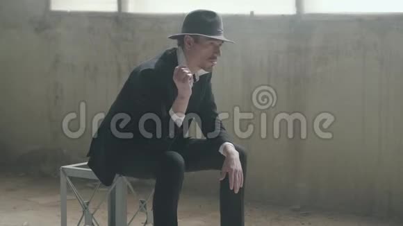 肖像英俊自信的男人戴着一顶帽子抛出并抓住硬币坐在一座废弃的建筑他的头视频的预览图