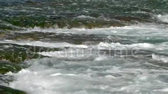 从棕色岩石中流出白色泡沫的无尽海浪视频的预览图