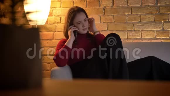 在室内一间舒适的公寓里年轻漂亮的白种人女性在电话中愉快地交谈视频的预览图