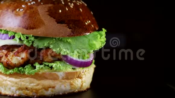 快餐特写有烤排骨青菜番茄和洋葱的汉堡在黑色的木板上慢慢旋转视频的预览图