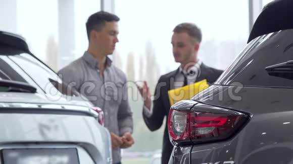 有选择地关注一辆车男性客户在后台与汽车经销商交谈视频的预览图