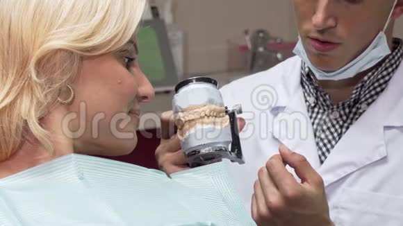 在诊所工作的男牙医向病人展示牙模视频的预览图