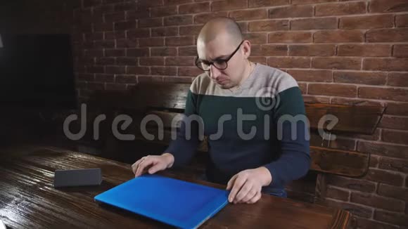 办公室里戴眼镜的商人打开笔记本电脑开始在键盘上打字视频的预览图