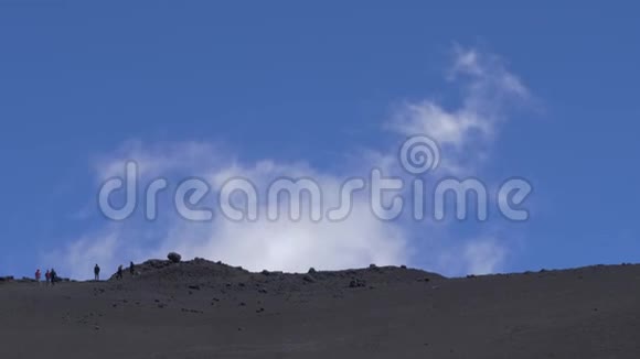 人们沿着埃特纳火山上的熔岩化石行走火山表面上方的白云意大利西西里视频的预览图