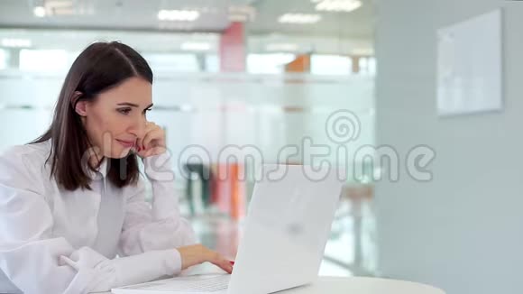 办公室里的女孩拿着笔记本电脑紧紧地看着显示器视频的预览图