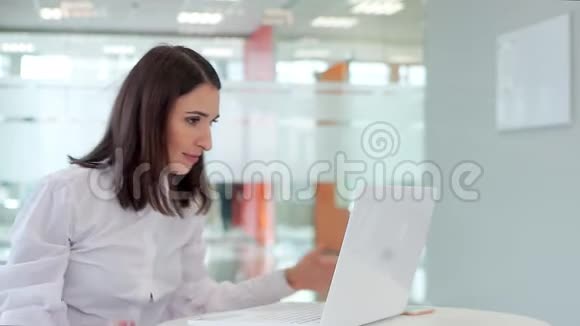 办公室里的女孩拿着一台笔记本电脑紧紧地看着显示器高兴地尖叫起来看着相机视频的预览图