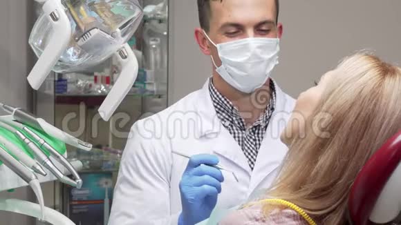 男性牙医戴医药口罩检查女性病人牙齿视频的预览图