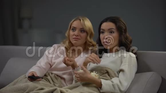 两个震惊的女人吃爆米花看有趣的电视节目休息视频的预览图