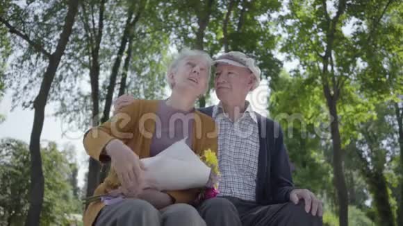 一对恋爱中的成熟夫妇坐在公园的长凳上的肖像可爱的女人和老人在一起投标视频的预览图