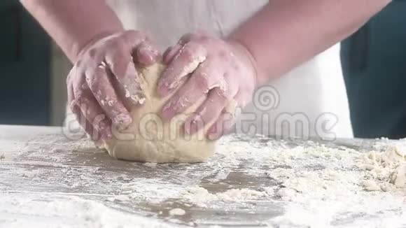 面包师把面团揉成馅饼用脏手把面团揉在桌子上特写慢动作视频的预览图