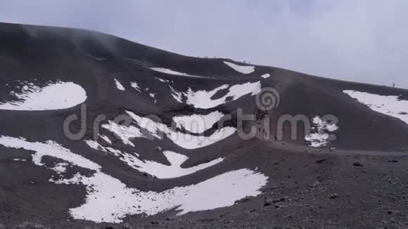 人们沿着埃特纳火山上的熔岩化石行走火山表面上方的白云意大利西西里视频的预览图