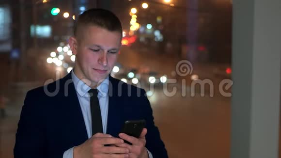 男商人看着智能手机和相机竖起大拇指窗外背景是视频的预览图