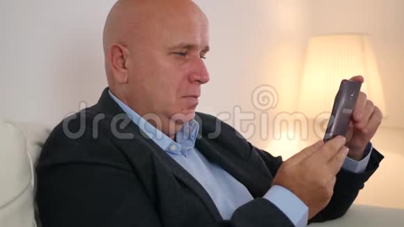 放松的商务人士坐在沙发上使用手机和饮酒视频的预览图