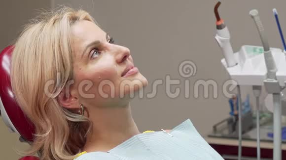 美丽成熟的女人开心地笑着坐在牙科椅上视频的预览图