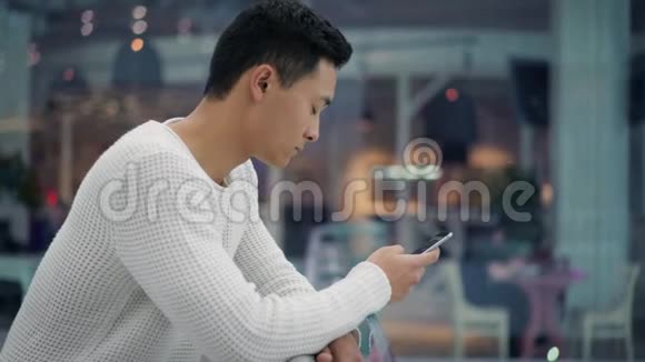 在大商场里带手机的亚洲男性简介视频的预览图