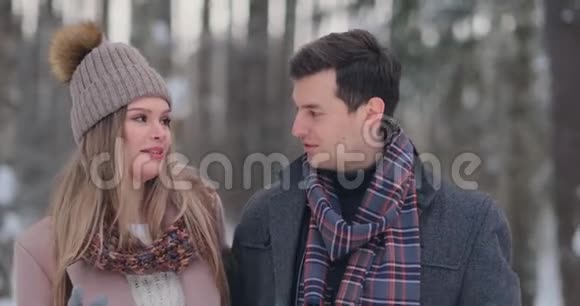 一个年轻的男人和一个穿着外套的女人正在冬天的森林里玩雪动作很慢幸福和幸福视频的预览图