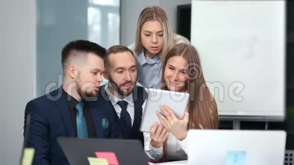 一群年轻友好的商务人士参加团队会议观看屏幕平板电脑视频的预览图