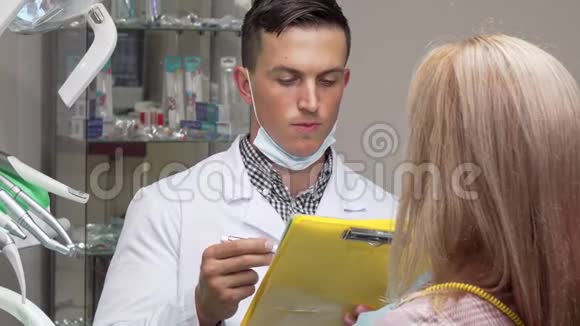 年轻的男牙医和他的女病人交谈检查医疗文件视频的预览图