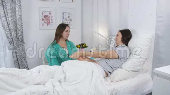 一个年轻的女孩来到医院和一个生病的妹妹坐在病房里说话视频的预览图