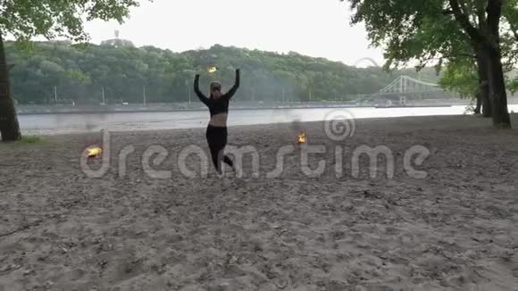 自信苗条的女人跳舞表演一个火球站在沙滩上的表演熟练的射击艺术家表现出熟练视频的预览图