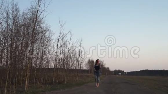 年轻女子在傍晚金色的一小时日落时分在田野里叫背景是晴朗的蓝天视频的预览图