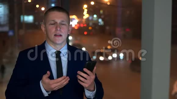 一个穿西装的男人拿着智能手机和相机说话视频的预览图