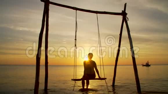 日落时海边秋千上的女孩视频的预览图