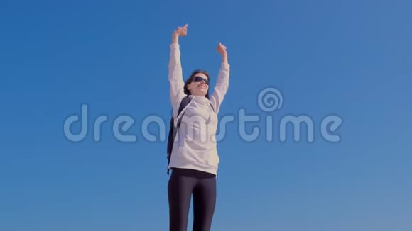 胜利获胜的幸福女人举手站在蓝天背景上视频的预览图