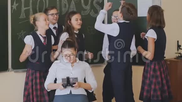 穿着校服的快乐学生在看电话的老师附近享受着学校假期的开始视频的预览图