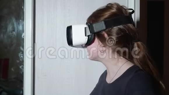 年轻的白种人女孩戴着VR眼镜看着周围的恐惧按下衣柜的门视频的预览图