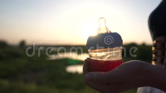 日落时分一个女孩在大自然的背景下合上婴儿瓶视频的预览图