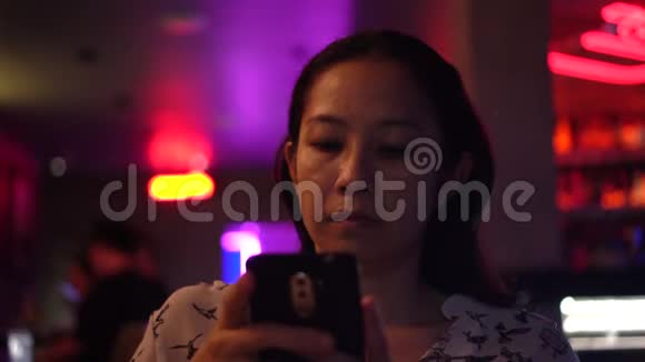 亚洲女人用红色霓虹灯现代夜总会的智能手机视频的预览图
