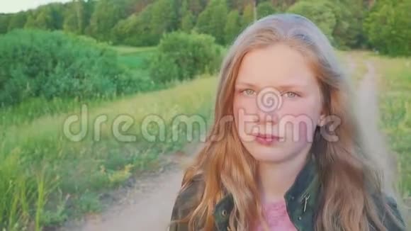 一个穿着军服的少女在森林附近的田野里漫步这孩子有一头金发慢动作视频的预览图