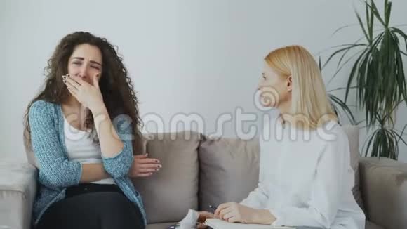 哭的压力很大的女人和专业的女心理学家交谈她给自己的纸纸巾擦去眼泪视频的预览图