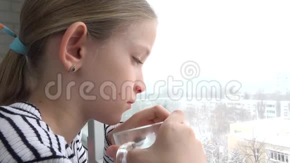 生病的孩子望着窗外悲伤的孩子脸在喝茶暴风雪的冬天视频的预览图
