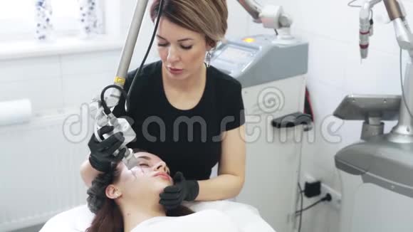 慢动作美容师为特殊设备的女性做激光面部剥皮视频的预览图
