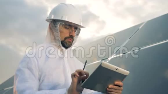 穿着防护服的人正在操作一块平板电脑旁边是一个巨大的太阳能装置视频的预览图