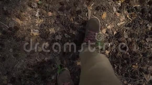 从眼睛往下看一个穿着棕色裤子和带红色鞋带的男人穿过树林相机视频的预览图