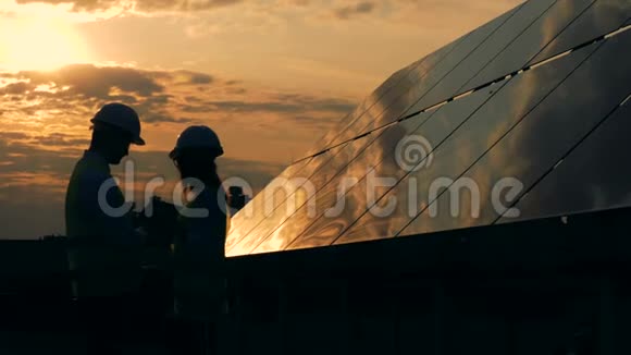 太阳能电池板和两名工人剪影交谈视频的预览图