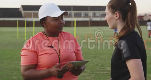 年轻的成年女性橄榄球运动员和训练教练视频的预览图