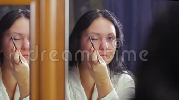 一个穿着白大褂的年轻女人在镜子前做眼妆视频的预览图