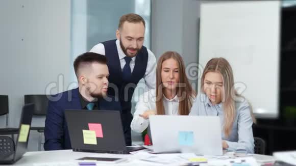 一群商业人士讨论在现代办公室工作看着屏幕笔记本电脑视频的预览图