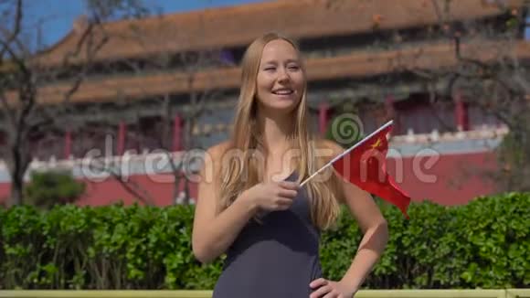 慢镜头拍摄一位女博主微笑着手中拿着一面中国小旗旅游中国概念视频的预览图