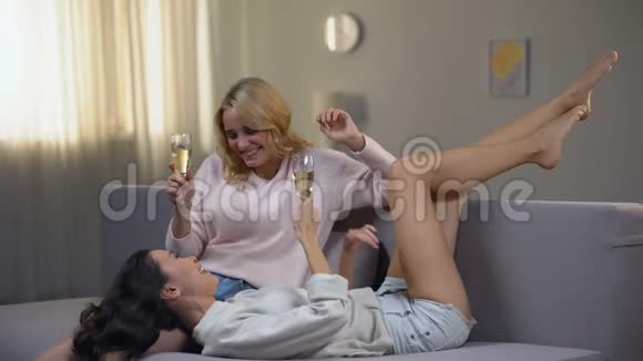 年轻女子开心地笑着喝着香槟一起玩视频的预览图